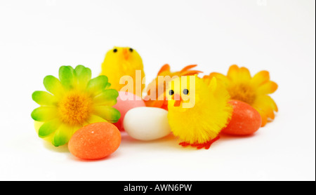 Drei Küken, dekorative Blumen und Süßigkeiten Eiern Stockfoto