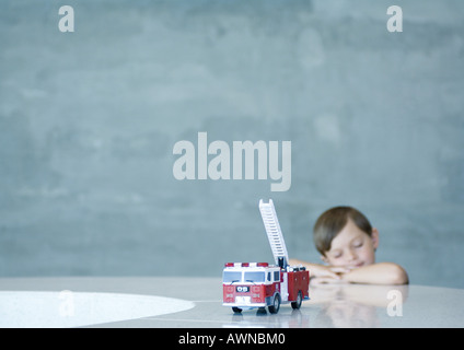 Junge träumt hinter Spielzeug Feuerwehrauto Stockfoto