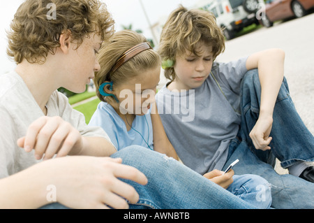 Kinder sitzen in der Straße, eine mit MP3-player Stockfoto