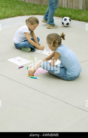 Mädchen sitzen auf Auffahrt, Malerei und Zeichnung Stockfoto