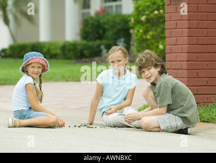 Drei Kinder spielen Murmeln im freien Stockfoto
