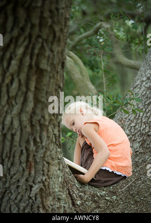 Mädchen im Baum lesen Stockfoto