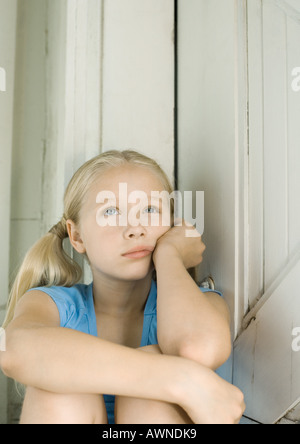 Mädchen Kopf haltend, Blick nach oben Stockfoto