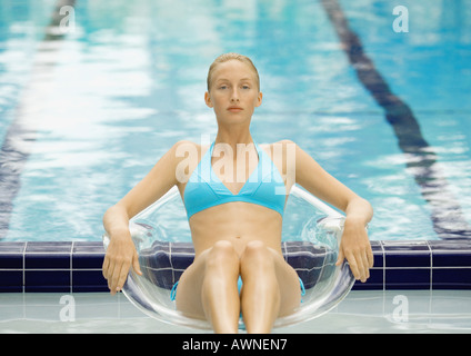Frau im Bikini sitzen in transparenten Stuhl pool Stockfoto