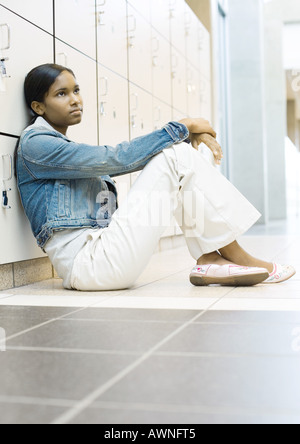 Teenager-Mädchen sitzen auf Boden, lehnte sich gegen Schließfächer Stockfoto