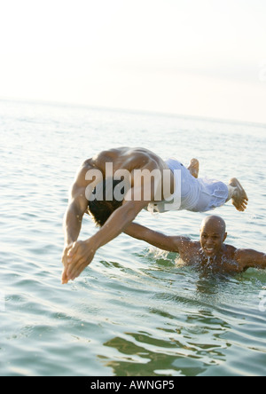 Mann aus Schultern des zweiten Mannes ins Wasser tauchen Stockfoto