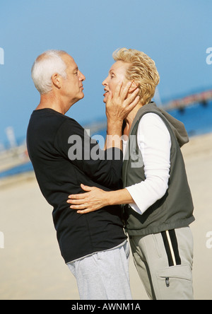 Reifen Sie paar stehen am Strand, umarmen, Seitenansicht Stockfoto