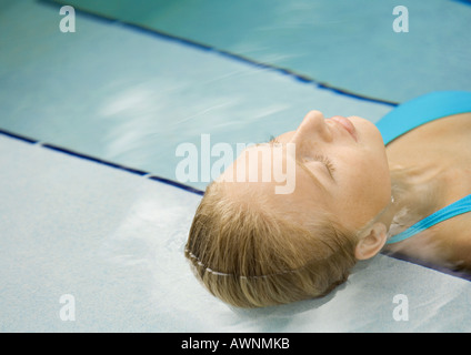 Frau liegend im Pool, Kopf auf Schritte Stockfoto