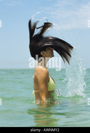 Frau im Meer stehen, wirft Haar Stockfoto