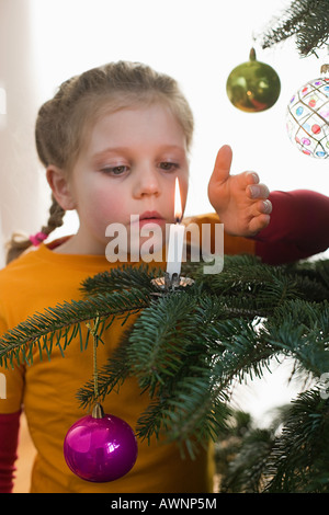 Ein Mädchen und eine Kerze auf einem Weihnachtsbaum Stockfoto