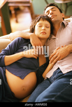 Schwangere Frau und Mann auf Sofa schlafen Stockfoto