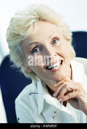 Geschäftsfrau hält Gläser, lächelnd in die Kamera, Porträt Stockfoto