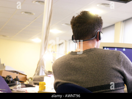 Mann trägt Kopfhörer und sitzen am Computer, Rückansicht Stockfoto