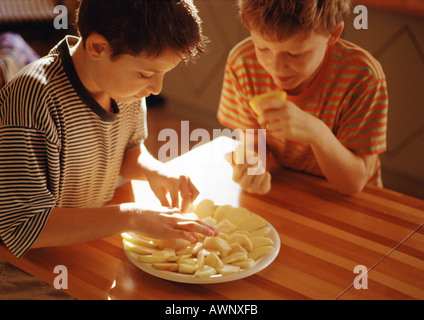 Ein Kind, Platte, zweite Kind hält Zitrone Hälften Apfelscheiben Inverkehrbringen Stockfoto