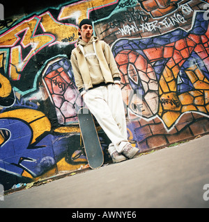 Junger Mann mit Skateboard schiefen Wand Graffitied, Porträt Stockfoto