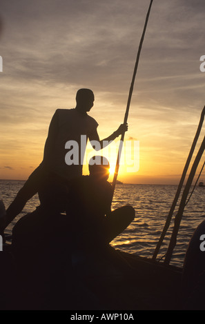 Einheimische Männer Segeln einer Dhau auf eine Bootsfahrt bei Sonnenuntergang an der Küste, die Insel Sansibar, Tansania Stockfoto