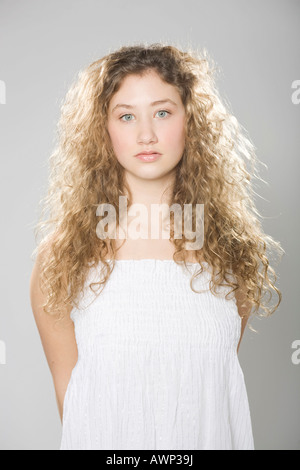 Junge Frau mit langen, lockigen Haaren, trägt ein weißes Kleid Stockfoto