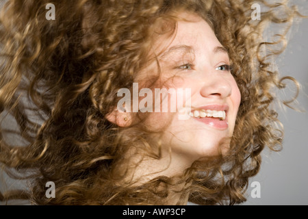 Junge Frau, ihr langes lockiges Haar durch die Luft fliegen Stockfoto