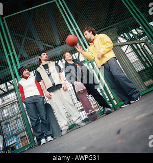 Junge Menschen stehen gegen Zaun, ein Spinnen-basketball Stockfoto