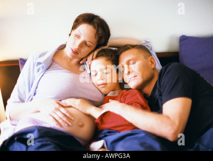 Schwangere Frau mit Mann und Kind im Bett sitzend Stockfoto