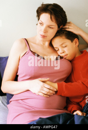 Schwangere Frau sitzt mit Kind Stockfoto