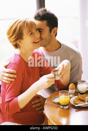 Schwangere Frau und Mann beim Frühstück, lächelnd Stockfoto