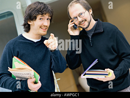 Zwei Männer auf der Suche in die Kamera, ein Hinweis, der andere mit Handy, Porträt Stockfoto