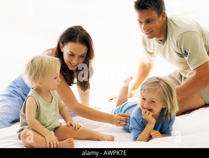 Familie zusammen im Bett, Eltern kitzeln kleines Mädchen Stockfoto