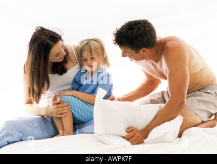 Familie zusammen auf Bett, Mutter-Holding-Tochter auf Schoß Stockfoto