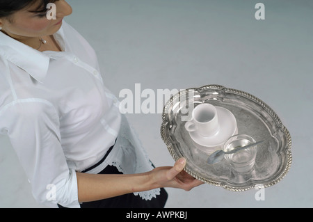 Kellnerin mit einer Tasse Kaffee und ein Glas Wasser auf einem silbernen Tablett Stockfoto