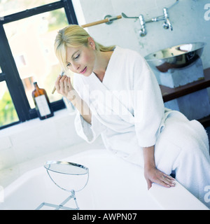 Frau Anwendung Make-up im Badezimmer Stockfoto