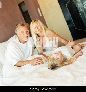 Mädchen auf dem Bett liegend mit Eltern Stockfoto