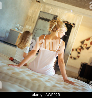 Mutter und Tochter sitzen auf Bett, Rückansicht Stockfoto
