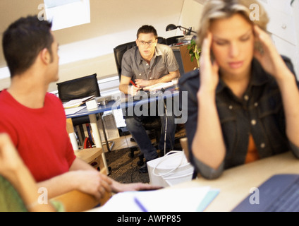 Männer sprechen im Amt, Frau Kopf haltend Stockfoto