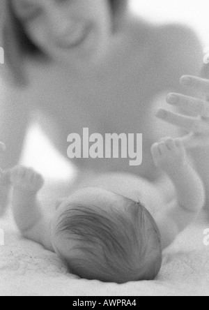 Baby liegend mit Mutters Finger mit Hand, b&w Stockfoto