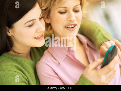 Zwei junge Frauen, eine mit Arme um andere, mit Handy, Porträt Stockfoto