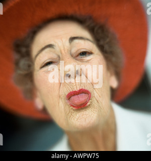 Porträt von senior Frau roten Hut mit Zunge heraus Stockfoto