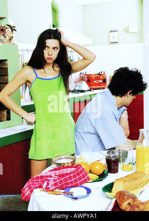 Zu zweit am Frühstückstisch, Mann sitzt abgewiesen, Frau stehen, auf der Suche nach unglücklich. Stockfoto