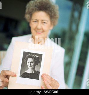 Ältere Frau zeigt Foto von sich selbst als jüngere Frau Stockfoto