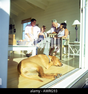 Vier Personen in einem Raum, Hund am Boden liegend Stockfoto