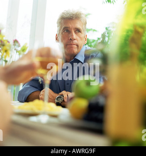 Reifer Mann am Tisch sitzen Stockfoto
