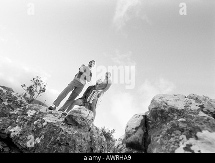 Zwei junge Menschen stehen auf Felsen, niedrigen Winkel Ansicht, b&w. Stockfoto