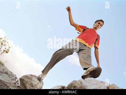 Junger Mann verstärkt über Felsen, niedrigen Winkel Ansicht. Stockfoto