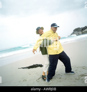 Älteres Paar spielen am Strand, Frau, Mann von hinten greifen Stockfoto