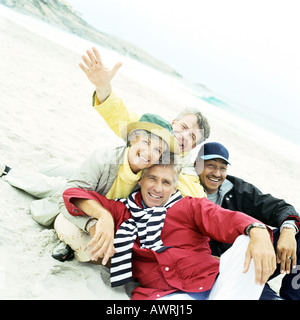 Ältere Gruppe sitzt am Strand in Kamera Stockfoto