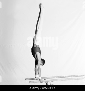 Junge männliche Turnerin tun Handstand am Barren, Seitenansicht Stockfoto