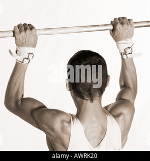 Männlichen Turner selbst hochziehen auf horizontale Leiste, Rückansicht Stockfoto