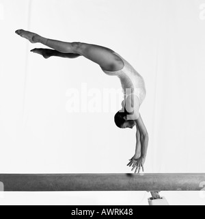 Junge weibliche Turnerin am Schwebebalken durchführen, mitten in der Luft, seitliche Ansicht Stockfoto