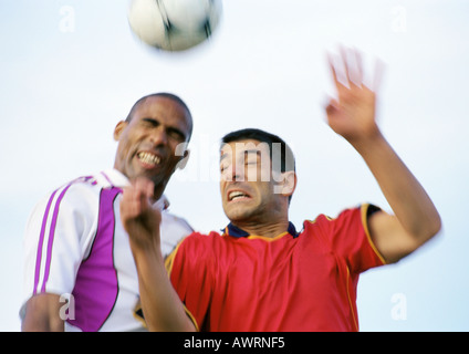 Zwei Spieler im Wettbewerb um den Ball bei einem Fußballspiel, verschwommen, Porträt. Stockfoto