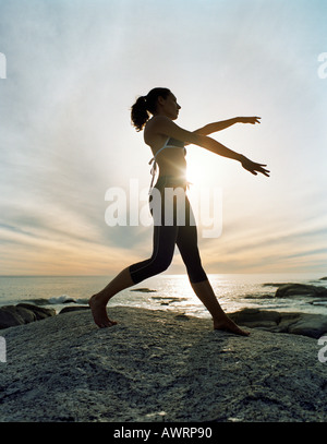 Frau, die Durchführung von Tai Chi am Strand, Silhouette Stockfoto